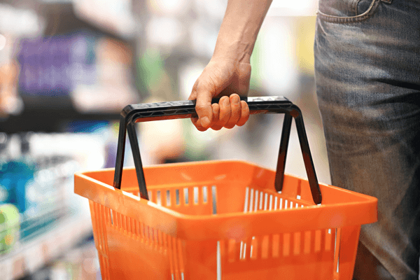a hand holding a shopping basket in a store
